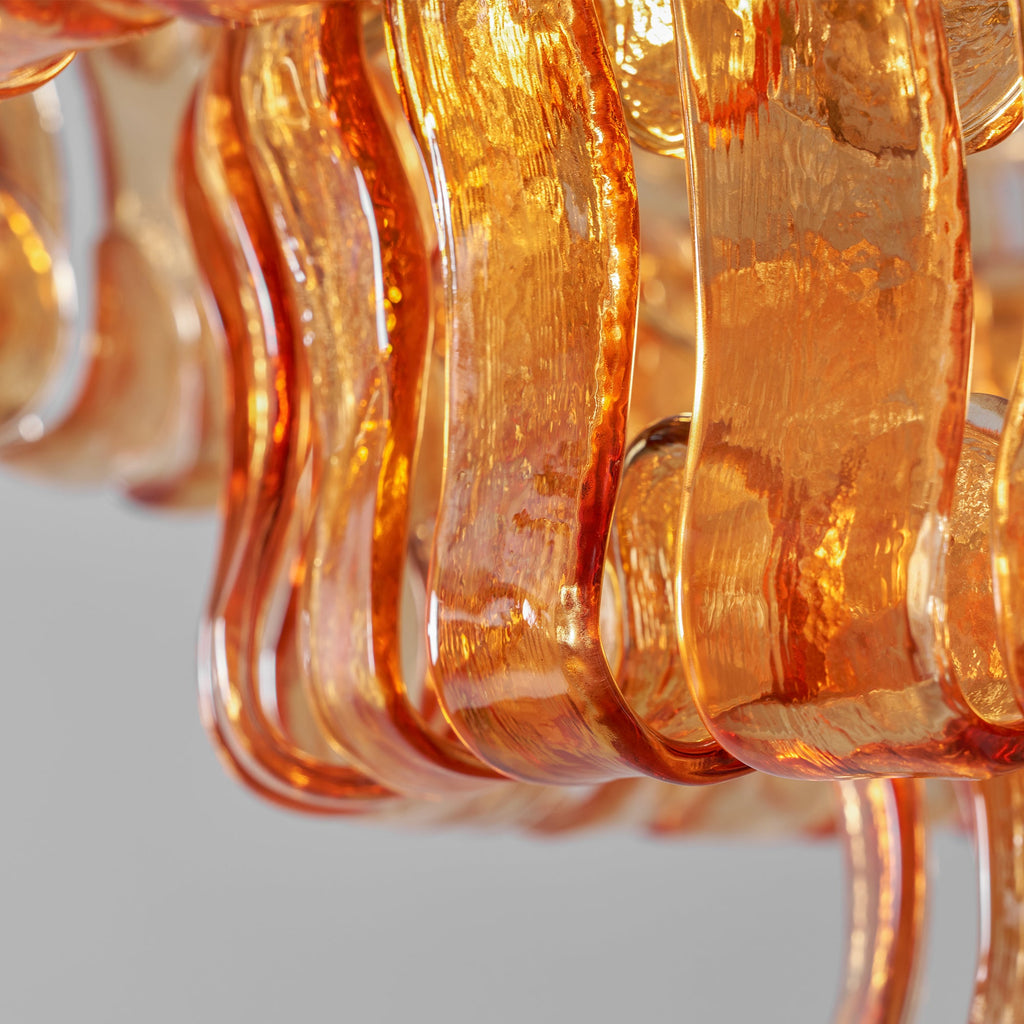 Close view of rippled amber glass strips on this Clérachic chandelier, the lit glass edges glowing orange.