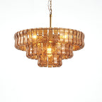 Peach-amber glass Clérachic chandelier with three tiers and warm bulbs lit inside, on a white background.
