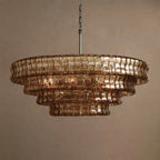 Brown-bronze Clérachic chandelier with five stepped glass tiers and a hint of warm light, on a tan backdrop.
