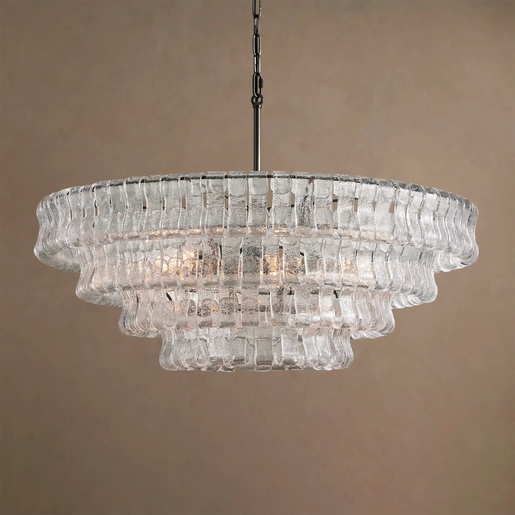 Clear glass tiers on this Clérachic chandelier, with a black chain, softly lit against a taupe backdrop.