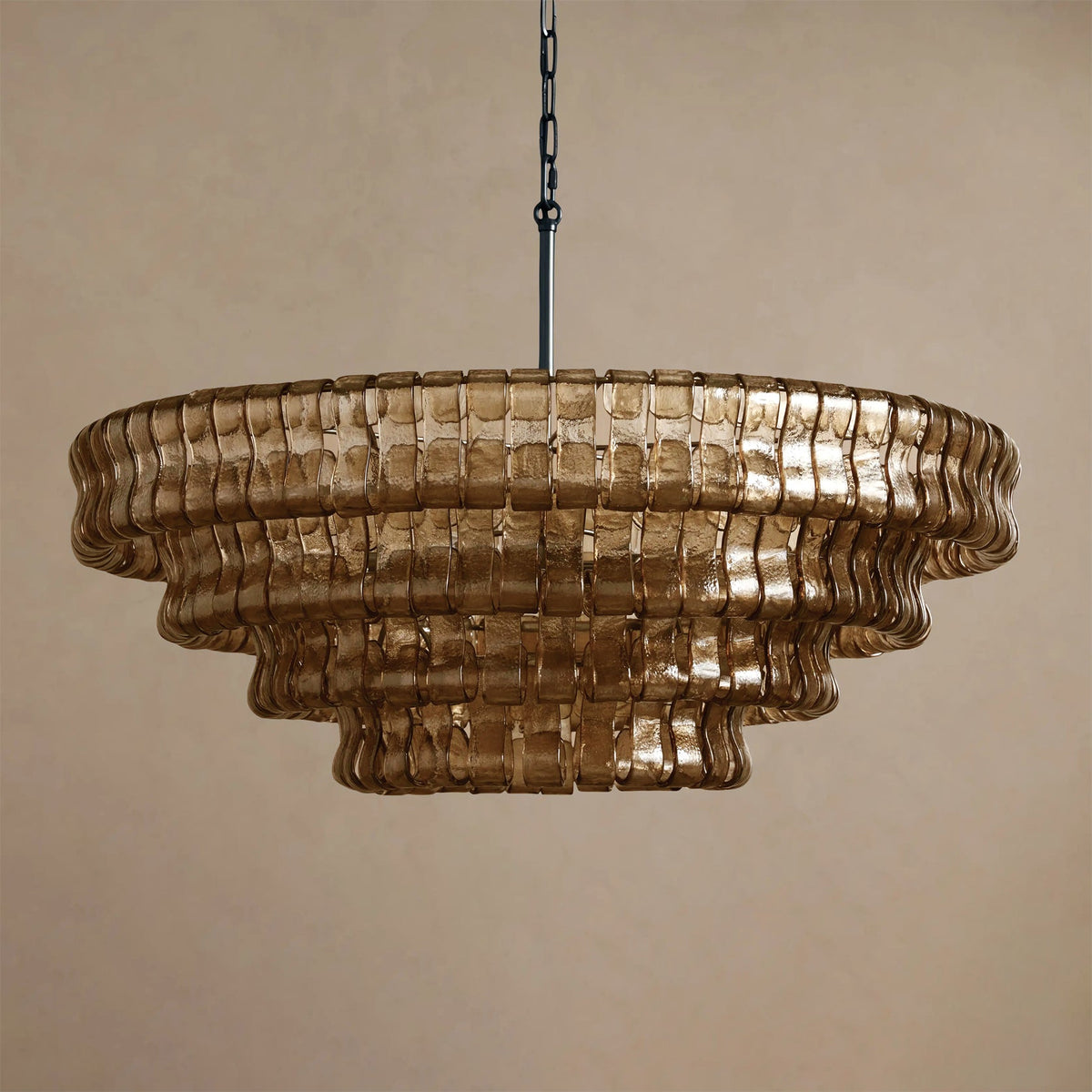 Deep brown glass in five rounded tiers on this Clérachic chandelier, hung from a black chain against a taupe backdrop.