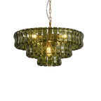 A green glass chandelier from Clérachic with a brass stem, lit warm inside, on a white backdrop.