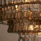 Close view of smoky bronze glass strips on this Clérachic chandelier, a warm glow shining through the ripples.