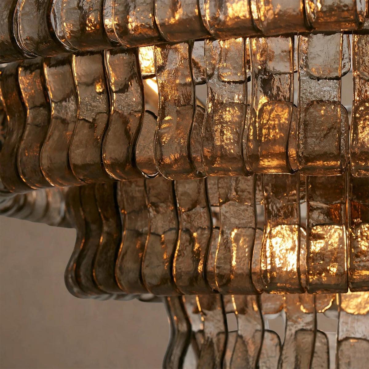 Close view of smoky bronze glass strips on this Clérachic chandelier, a warm glow shining through the ripples.