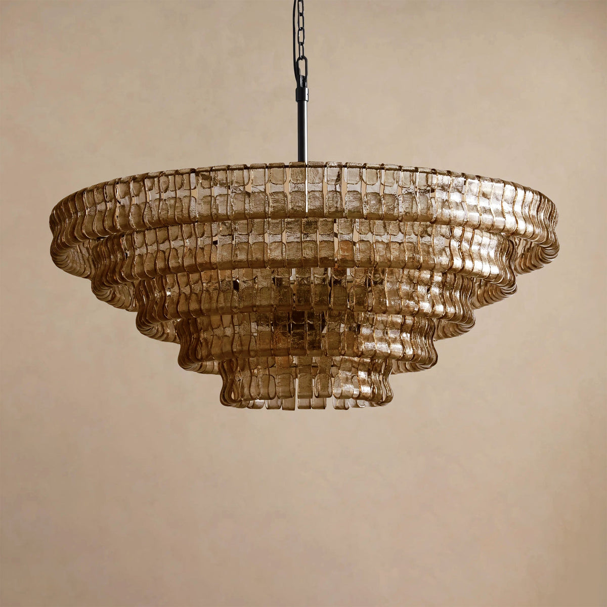 Honey-brown glass in five tiers on this Clérachic chandelier, hung from a black chain against a beige backdrop.