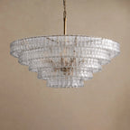On a brass stem, the five tiers of this clear glass Clérachic chandelier narrow toward the base, against a sand backdrop.