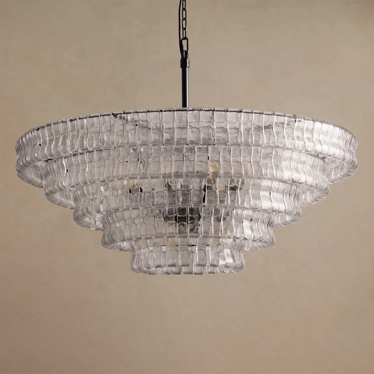 Wide clear-glass chandelier from Clérachic on a black chain, with a dark centre showing through the tiers, on tan.