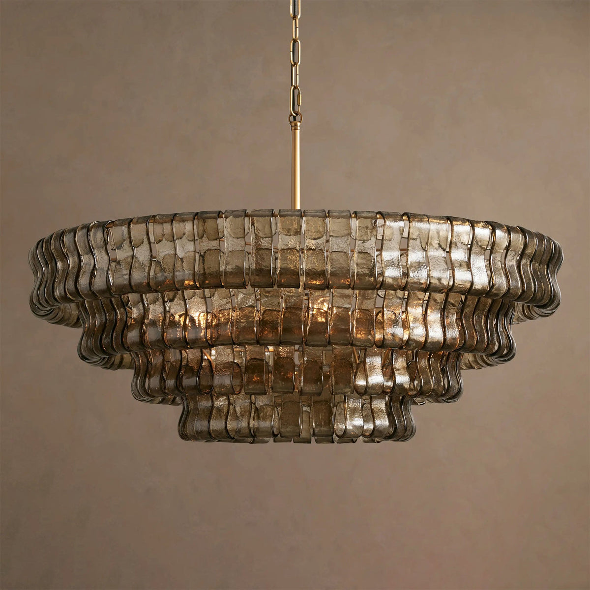 Smoke-grey glass and soft reflections on this Clérachic chandelier, five tiers on a brass stem against a taupe backdrop.