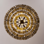 Looking straight up at a Clérachic chandelier, concentric rings of smoke-grey glass tiles circle a black spoked hub with bulbs.