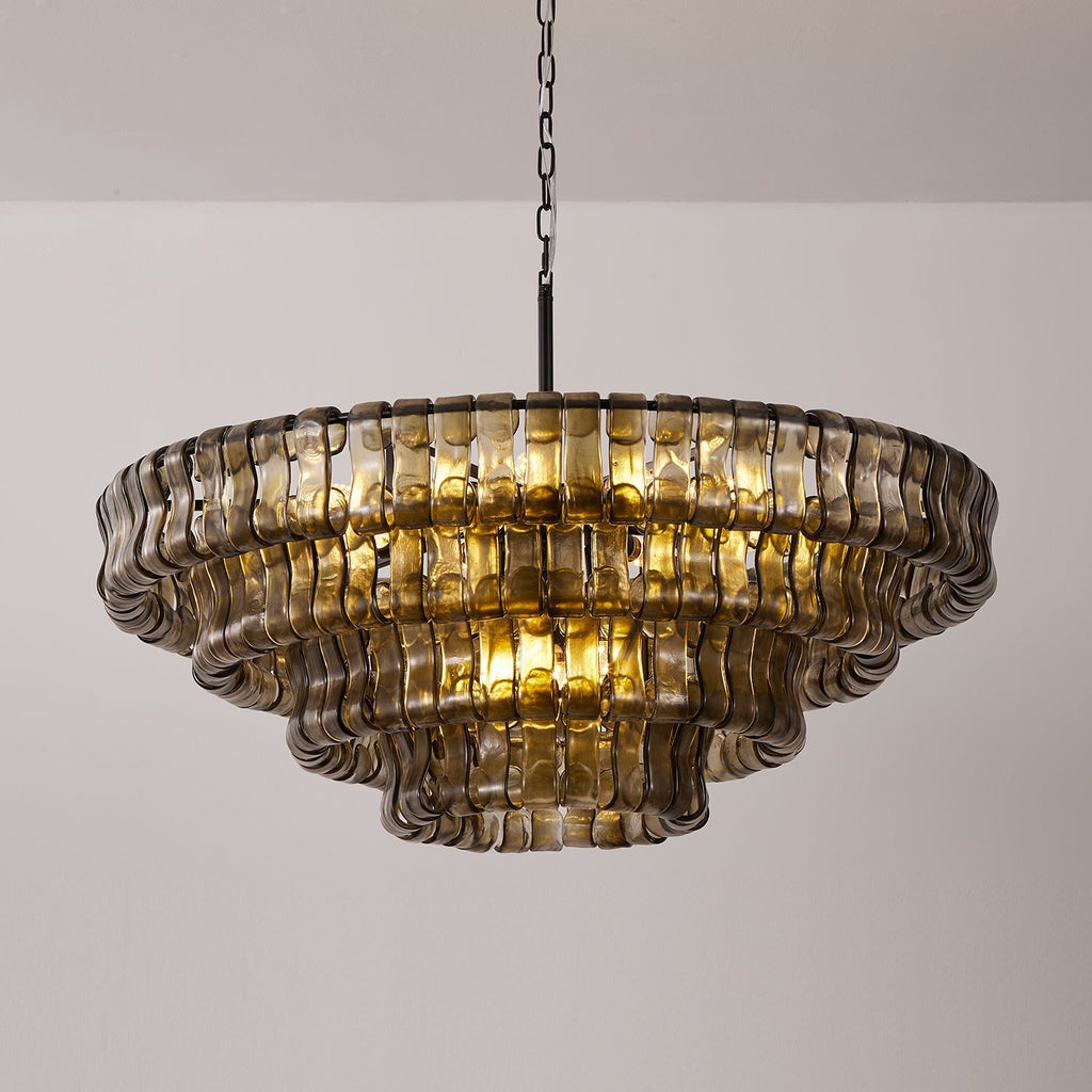 Lit gold inside, this smoke-grey Clérachic chandelier hangs on a black chain against a white wall and pale grey floor.