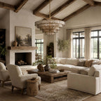 A smoke-grey Clérachic chandelier in a high-ceilinged living room with exposed beams, a stone fireplace and cream sofas.
