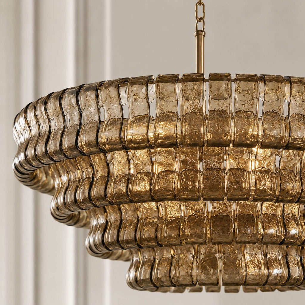 Close view of the stacked smoky-gold glass tiers and brass stem on this Clérachic chandelier, in soft daylight.