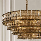 Close view of the stacked smoky-gold glass tiers and brass stem on this Clérachic chandelier, in soft daylight.