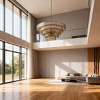 Champagne glass chandelier from Clérachic hanging in a double-height room with tall windows, a wood floor and a grey sofa.