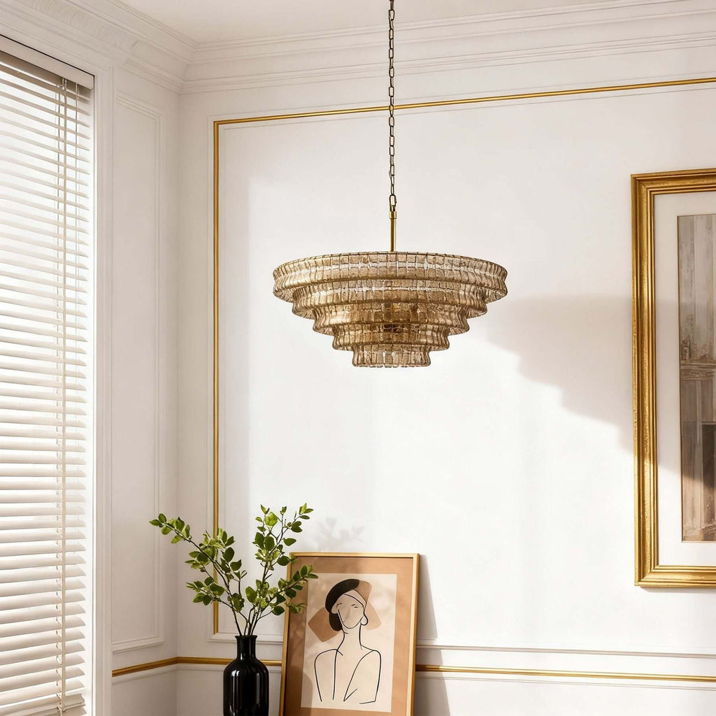 In a bright room with white panelling and gold trim, a champagne glass Clérachic chandelier hangs near a framed picture.