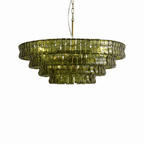 Whole on a white background, an olive-green glass Clérachic chandelier hangs from a brass-and-white chain.