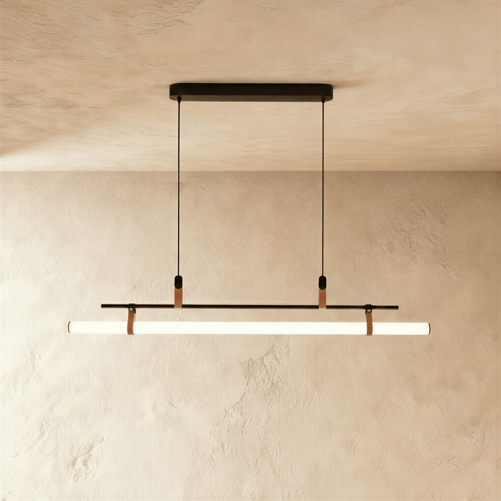 Clérachic linear pendant in black with a glowing white tube on leather straps, hung from a slim oval canopy on two cords.