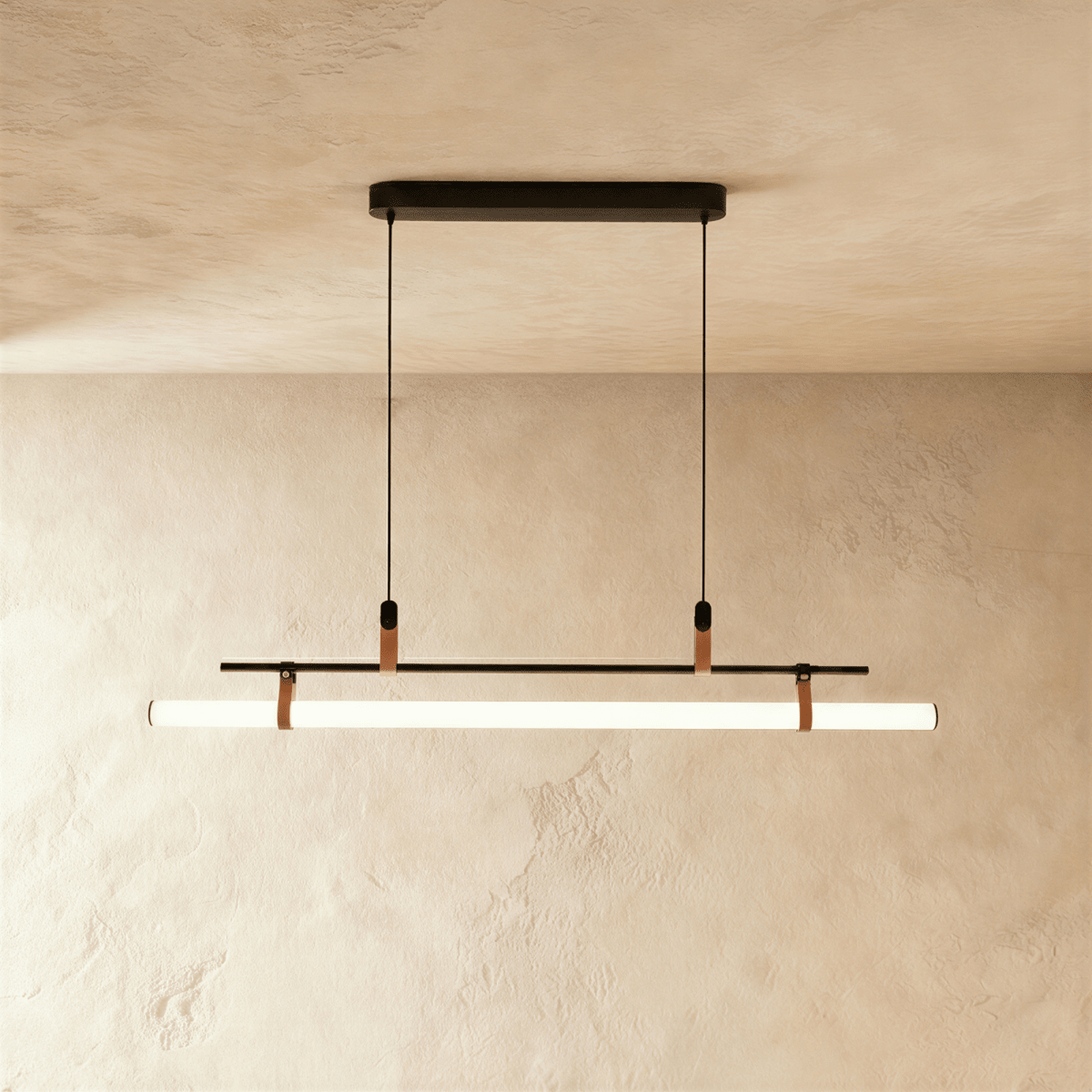Clérachic linear pendant in black with a glowing white tube on leather straps, hung from a slim oval canopy on two cords.