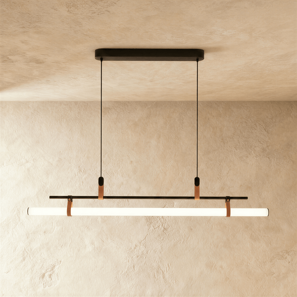 Clérachic longer black linear pendant, a lit opal tube strapped under a slim bar and hung from two cords on a plaster wall.