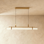 Clérachic linear pendant in brushed gold with a lit opal tube on tan straps, hung from a slim gold oval ceiling canopy.