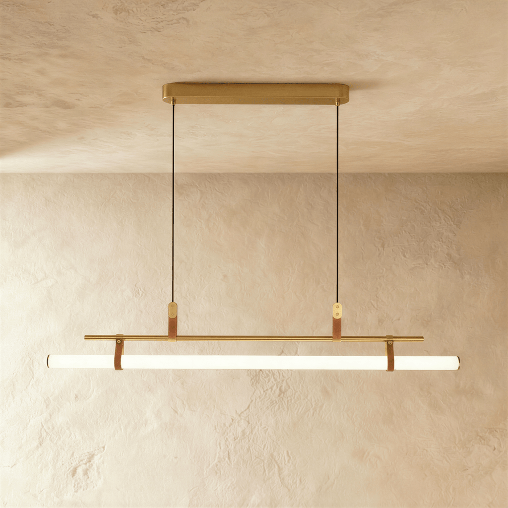 Clérachic longer gold linear pendant with a glowing white tube on leather straps, hung from a gold canopy on two cords.