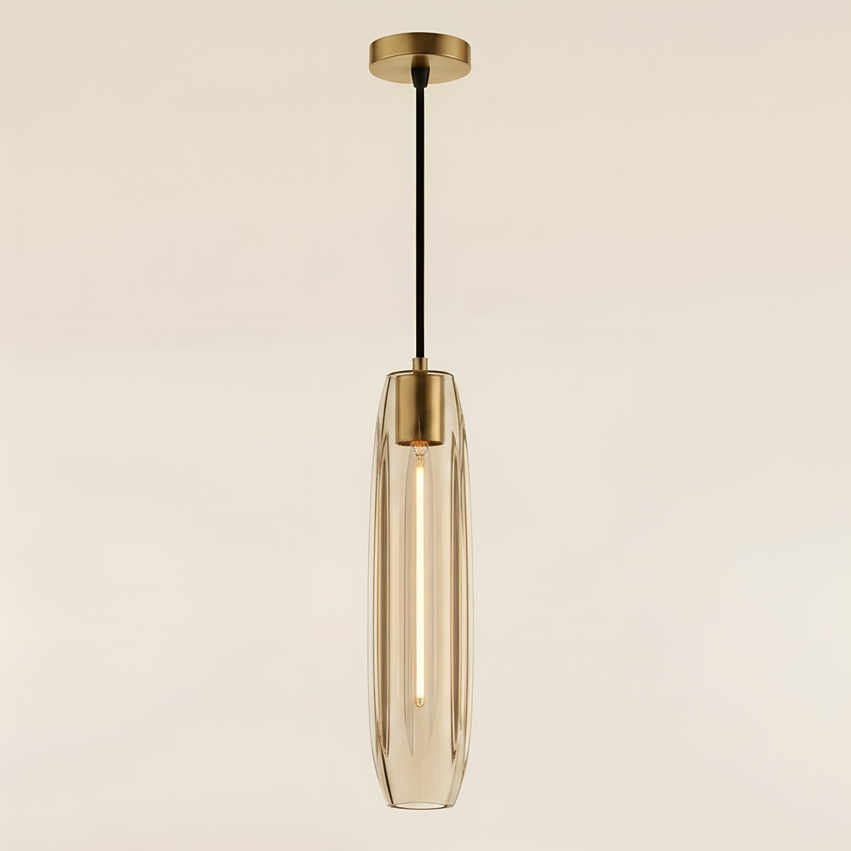 Clérachic glass tube pendant in champagne-tinted clear glass, lit so each vertical facet reads as a bright flute beneath its brass collar and ceiling plate