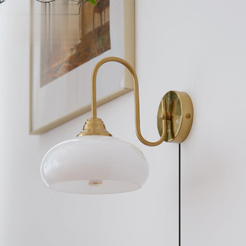 Clérachic glass wall lamp in copper with white glass and a plug-in cord, mounted beside a thin-framed print.