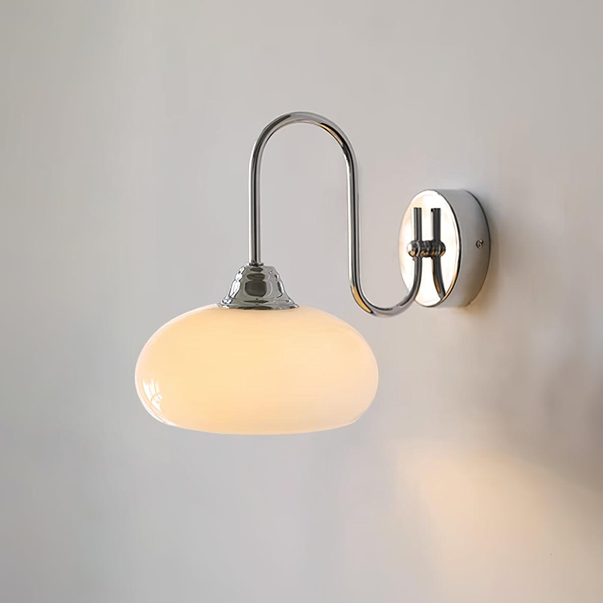 Clérachic glass wall lamp in chrome with a lit beige shade, hardwired so the S-curve arm shines on a pale wall.