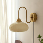 Clérachic glass wall lamp, copper and beige, plug-in beside sheer curtains, a dark headboard, and a plant sprig.