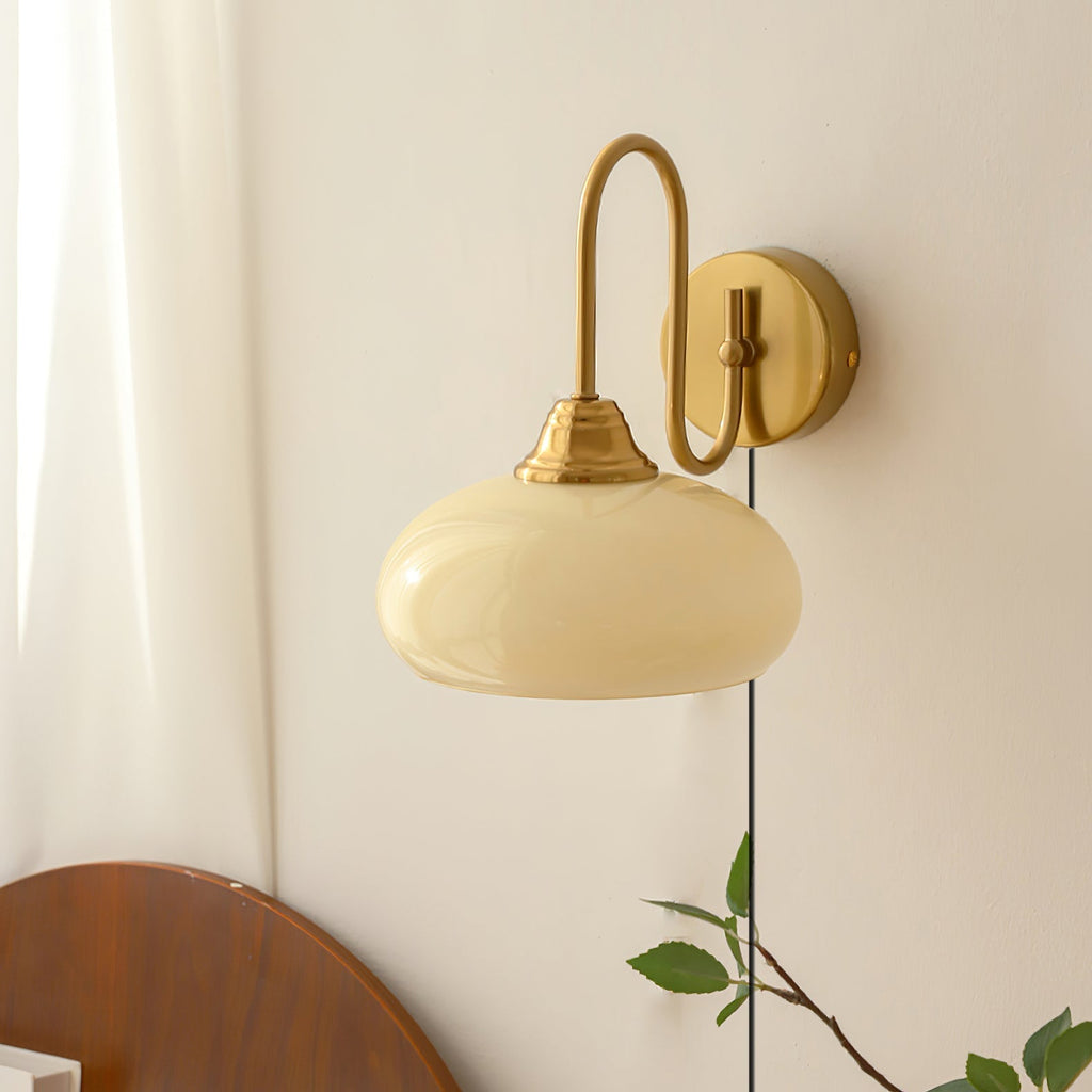 Clérachic glass wall lamp in copper and beige, plug-in above a curved wood headboard for bedside light.