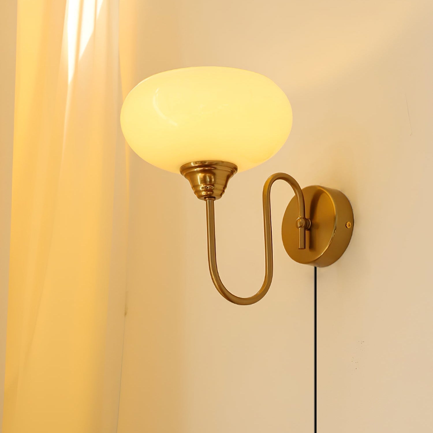 Clérachic glass wall lamp, copper arm and glowing beige glass, plug-in cord beside a soft curtain.