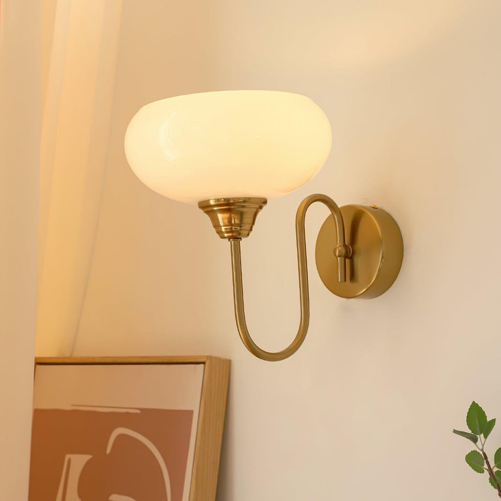 Clérachic glass wall lamp, copper arm and lit white glass, hardwired above terracotta art and a plant.
