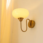 Clérachic glass wall lamp in copper with a glowing beige shade, hardwired beside a cream curtain.