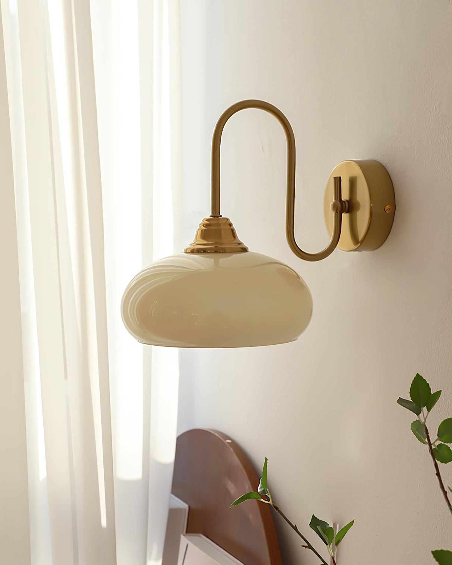 Clérachic glass wall lamp in copper and beige, hardwired in daylight above a rounded wood headboard.