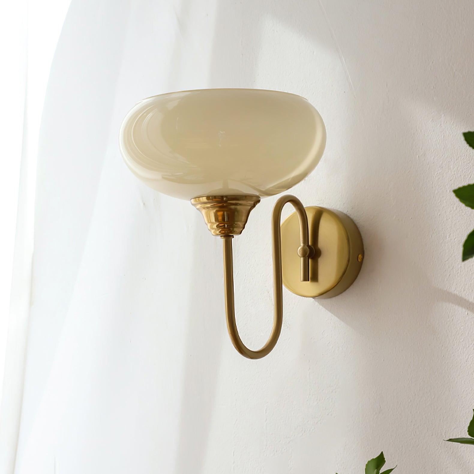 Clérachic glass wall lamp in copper with beige glass, hardwired U-arm seen beside a sheer curtain and leaves.