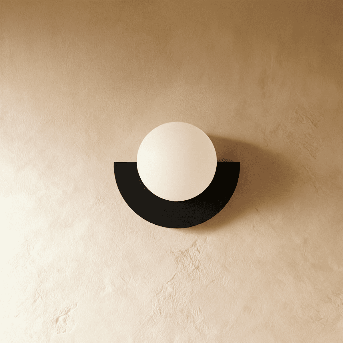 Clérachic opal glass globe on a black half-moon metal back plate, switched off, on a warm limewash plaster wall.