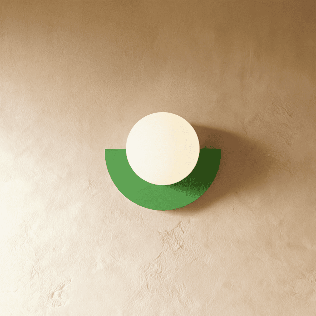 Clérachic lit opal glass globe on a green half-moon metal back plate, glowing gently on a limewash plaster wall.