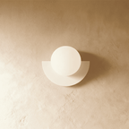 Clérachic opal glass globe on a white half-moon metal back plate, switched off, on a warm limewash plaster wall.