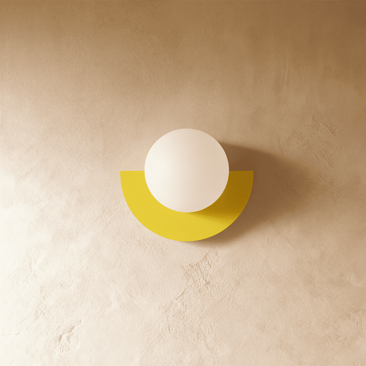 Clérachic lit opal glass globe on a yellow half-moon metal back plate, glowing softly on a limewash plaster wall.