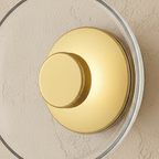 Close-up of the Clérachic glass uplight wall bowl in Transparent, showing its brass centre knob and clear glass rim.