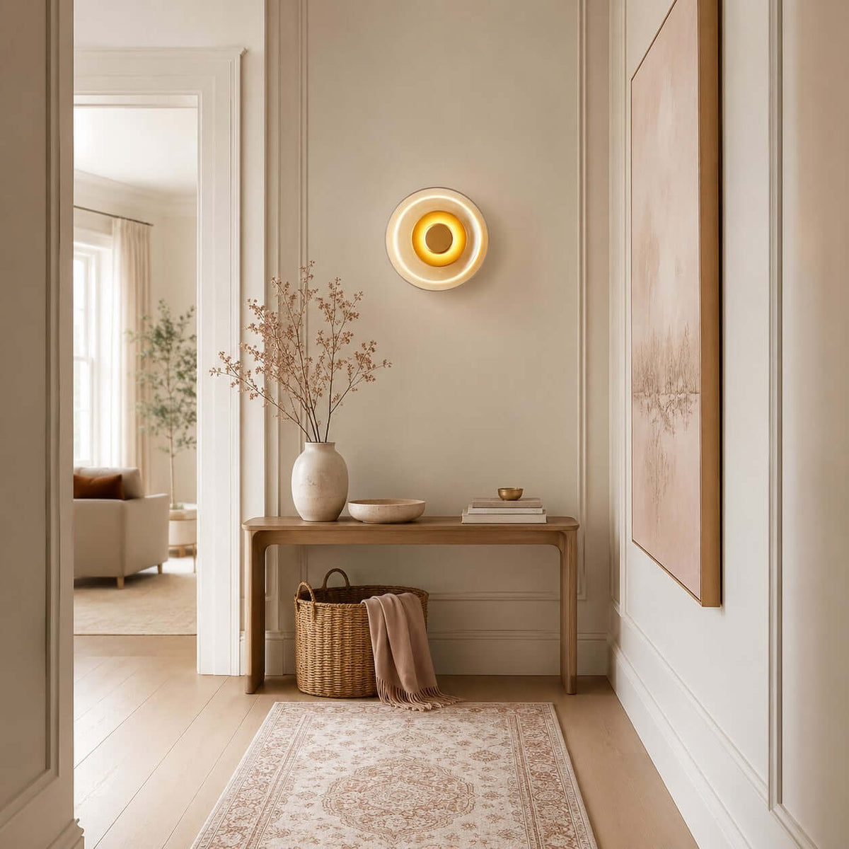 Small Clérachic wall light lit in a hallway above a wooden console, with a rug runner, a basket and a pink-toned painting.