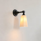 Black Clérachic wall light with a softly glowing tapered white shade, shown side-on against a pale wall.