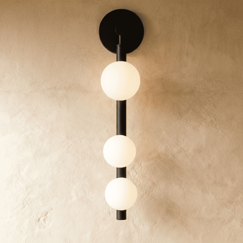Clérachic black wall lamp with three frosted glass spheres stacked down a slim vertical rod from a round backplate.