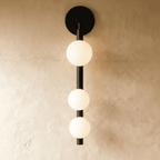 Clérachic black wall lamp with three frosted glass spheres stacked down a slim vertical rod from a round backplate.