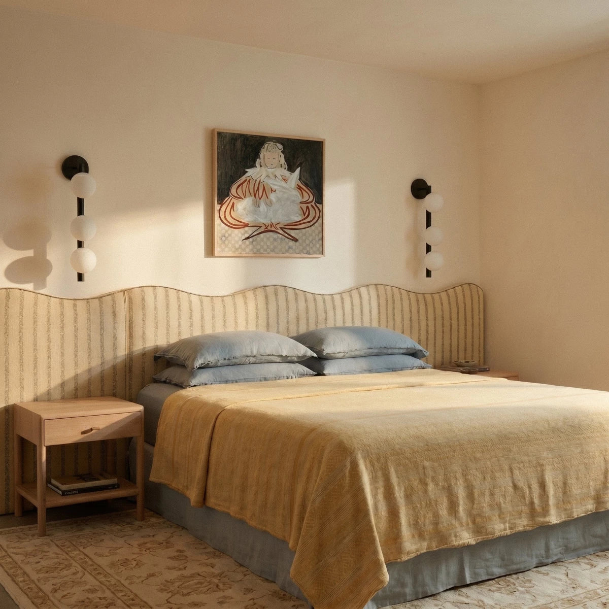 Pair of Clérachic black wall lamps with three frosted spheres each, flanking a painting above a wavy striped headboard.