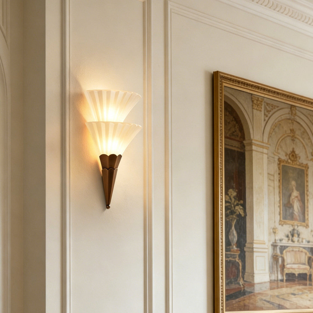 Two-cone Clérachic glass wall sconce glowing warm beside a large gilt-framed painting on a panelled wall.