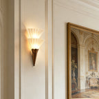 Two-cone Clérachic glass wall sconce glowing warm beside a large gilt-framed painting on a panelled wall.