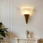 Single-cone Clérachic wall sconce with ribbed glass and a brown base, above a white mantel with a small cherub figure.