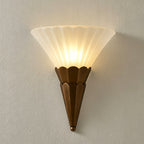 Close view of a single ribbed white glass cone on a scalloped brown base, lit, on this Clérachic wall sconce.