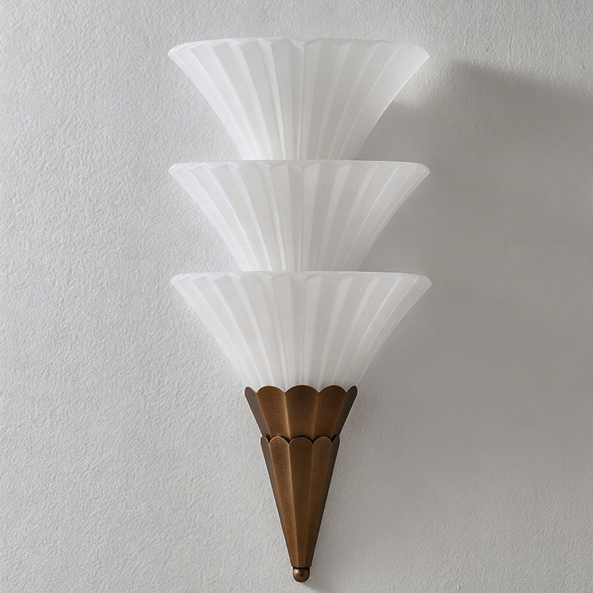 Unlit Clérachic wall sconce with three stacked frosted glass cones and a brown tapered base on a grey wall.